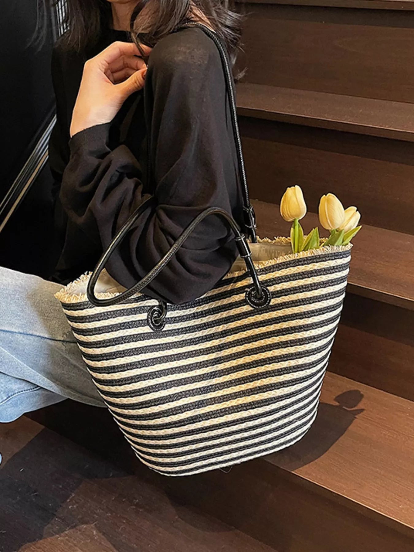 Woven straw tote bag with black-and-cream horizontal stripes, black top straps