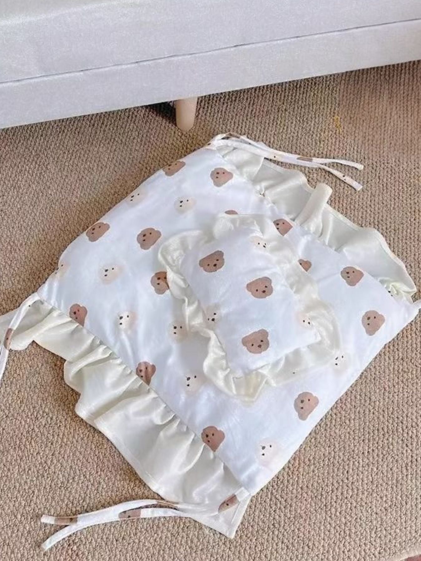 Bear-pattern pet bed cushion and pillow laid on the floor, white with brown prints.