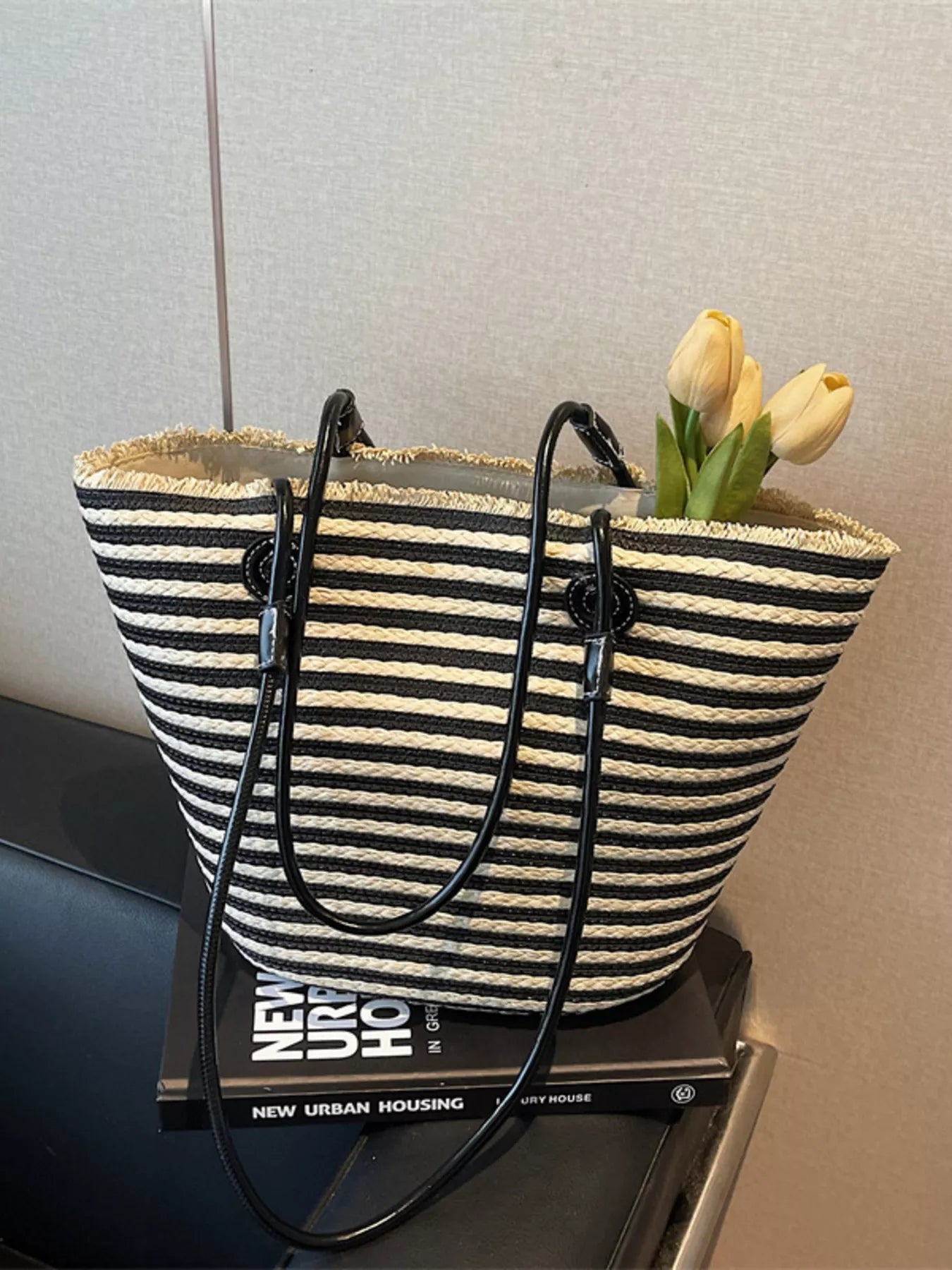 Black striped woven straw tote with long black handles and fringe top edge
