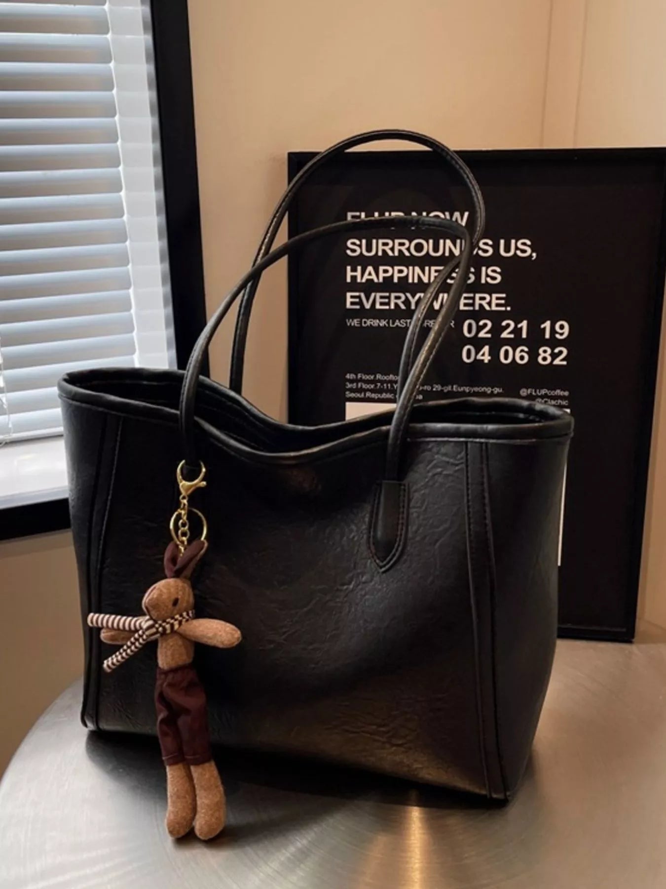Black leather tote shoulder bag with long handles and front slip pocket, charm keychain