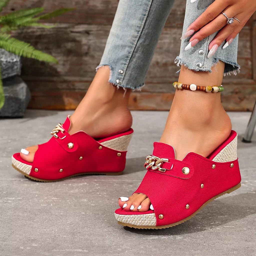 Rose red wedge sandals with open toe, studded front strap, and gold-tone chain buckle