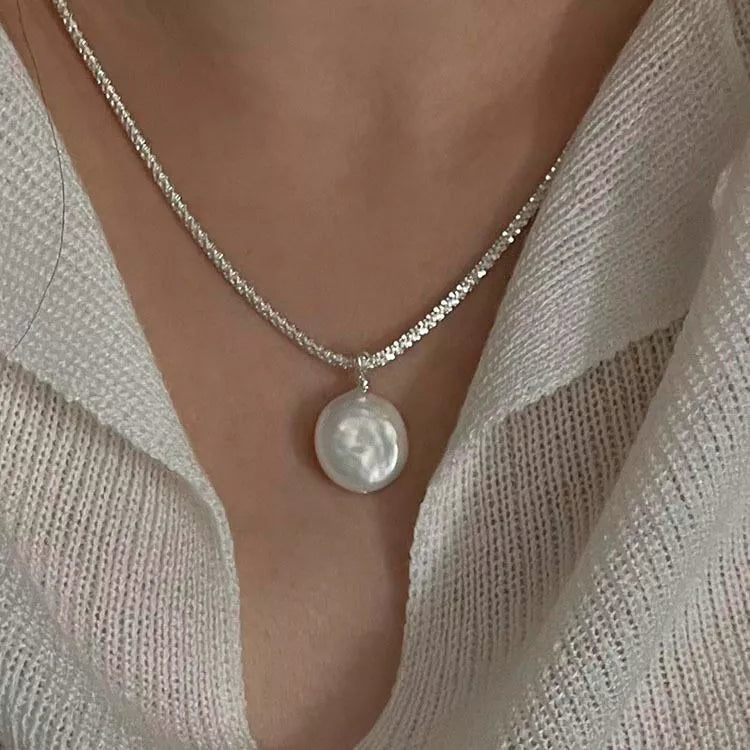 Close-up: silver chain necklace with large round pearl pendant