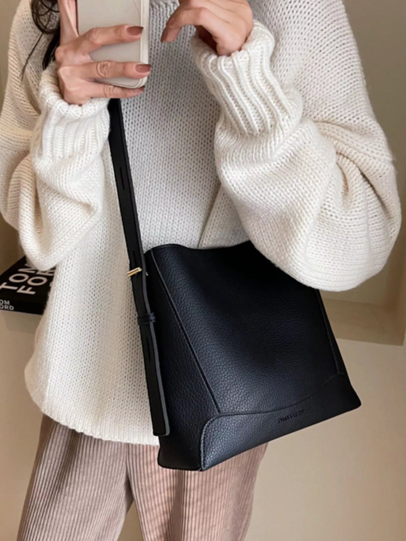 Black leather crossbody bag on strap with gold-tone hardware and zip-top