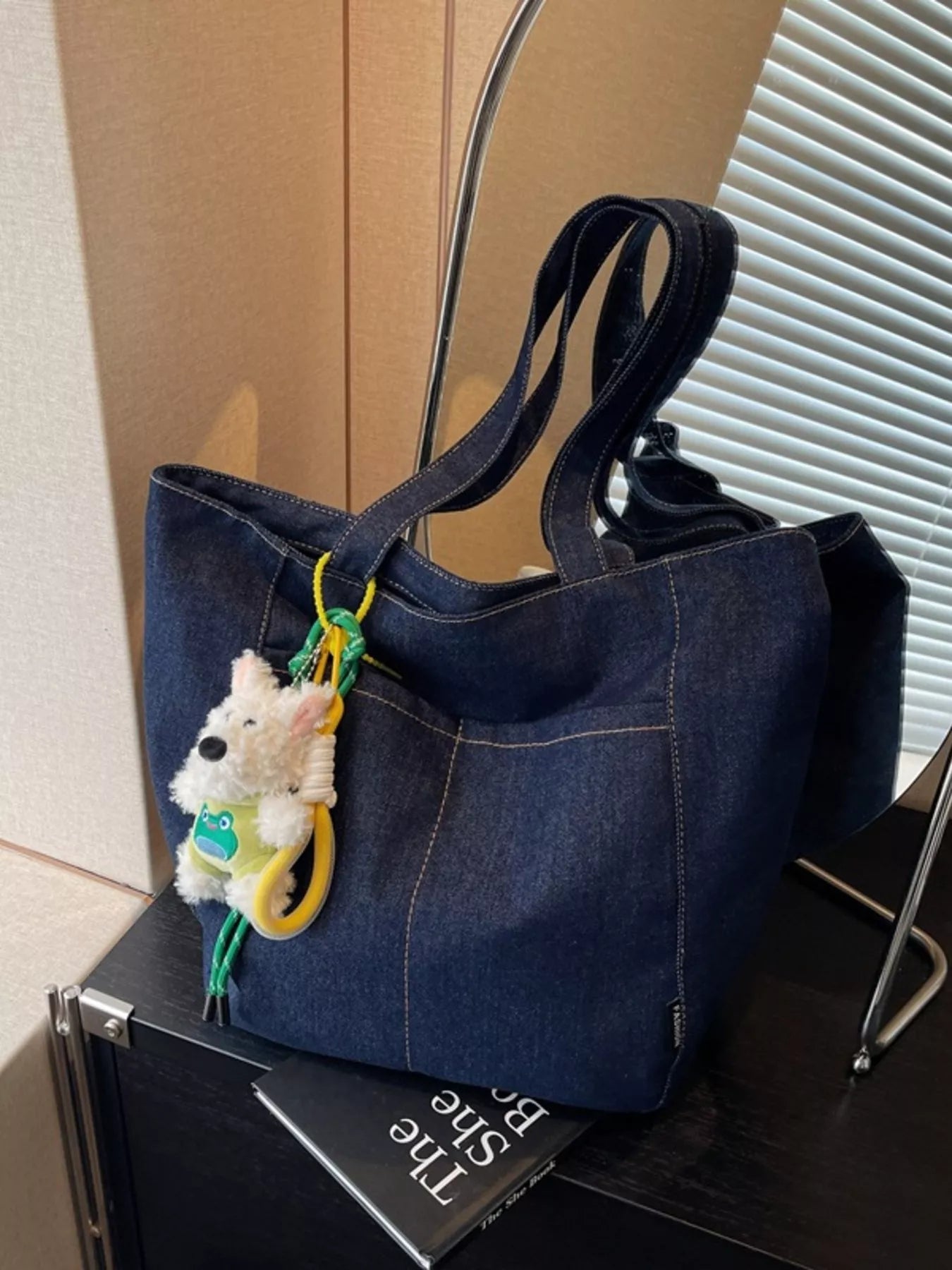 Dark navy denim tote with front seam panels and hanging plush charm keychain
