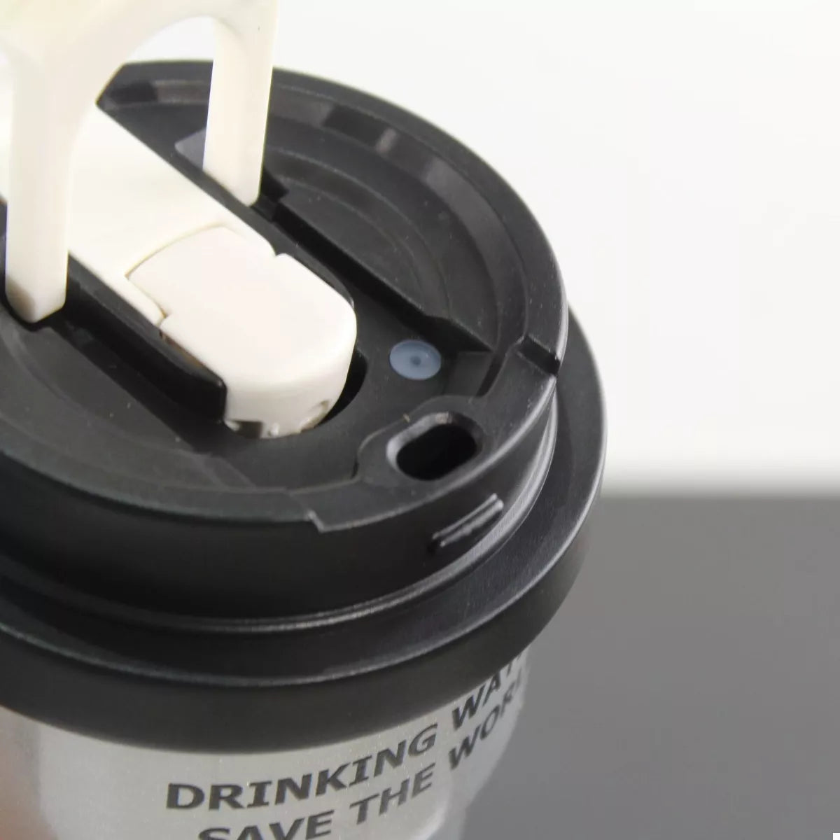 Black tumbler lid with straw inserted, drinking opening and latch detail