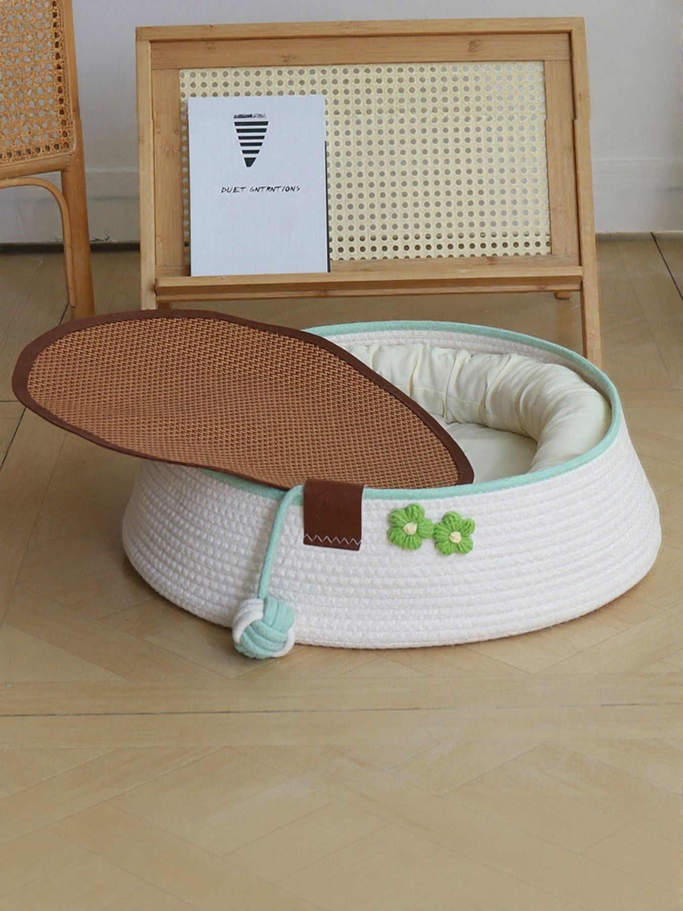 White woven pet nest with mint rim and green clover patch; brown lid flipped open