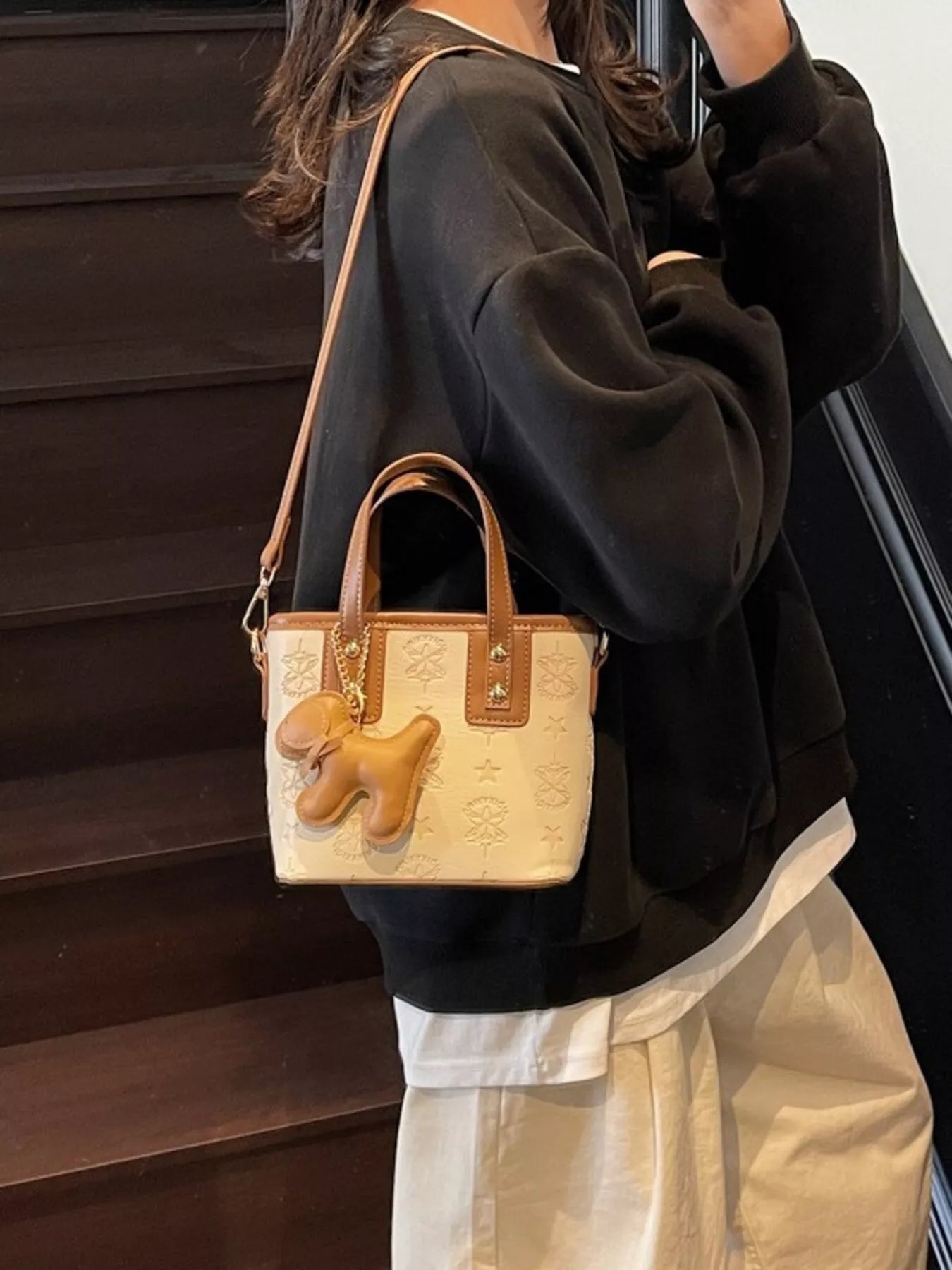 Beige Umhängetasche mit Relief-Sternen, Hund-Charm und Kettenanhänger am Vorderteil