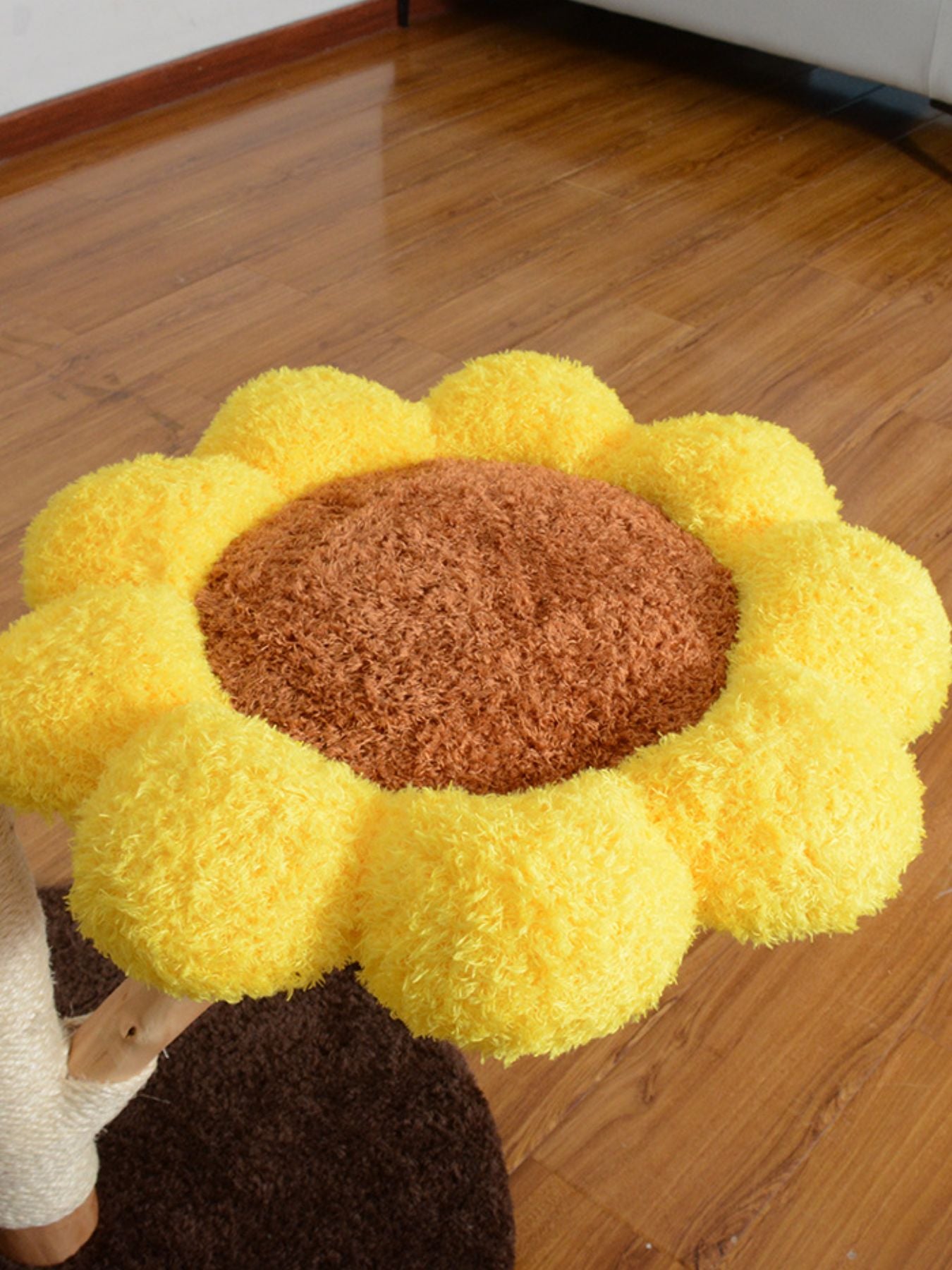 Cama tipo girasol amarilla con centro marrón en superficie mullida