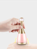 Blush pink facial steamer held by hand, gold wavy neck and white top