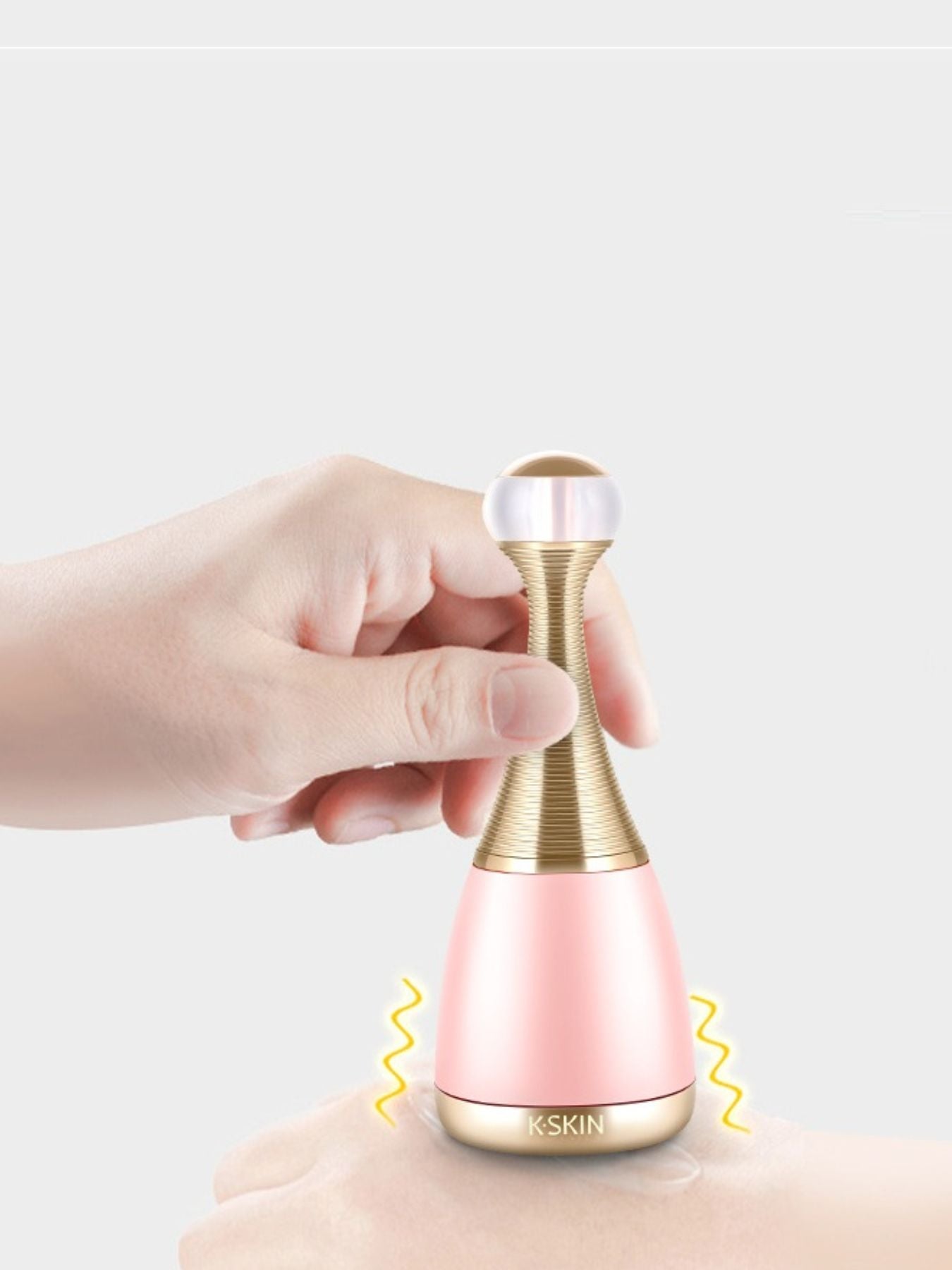 Blush pink facial steamer held by hand, gold wavy neck and white top