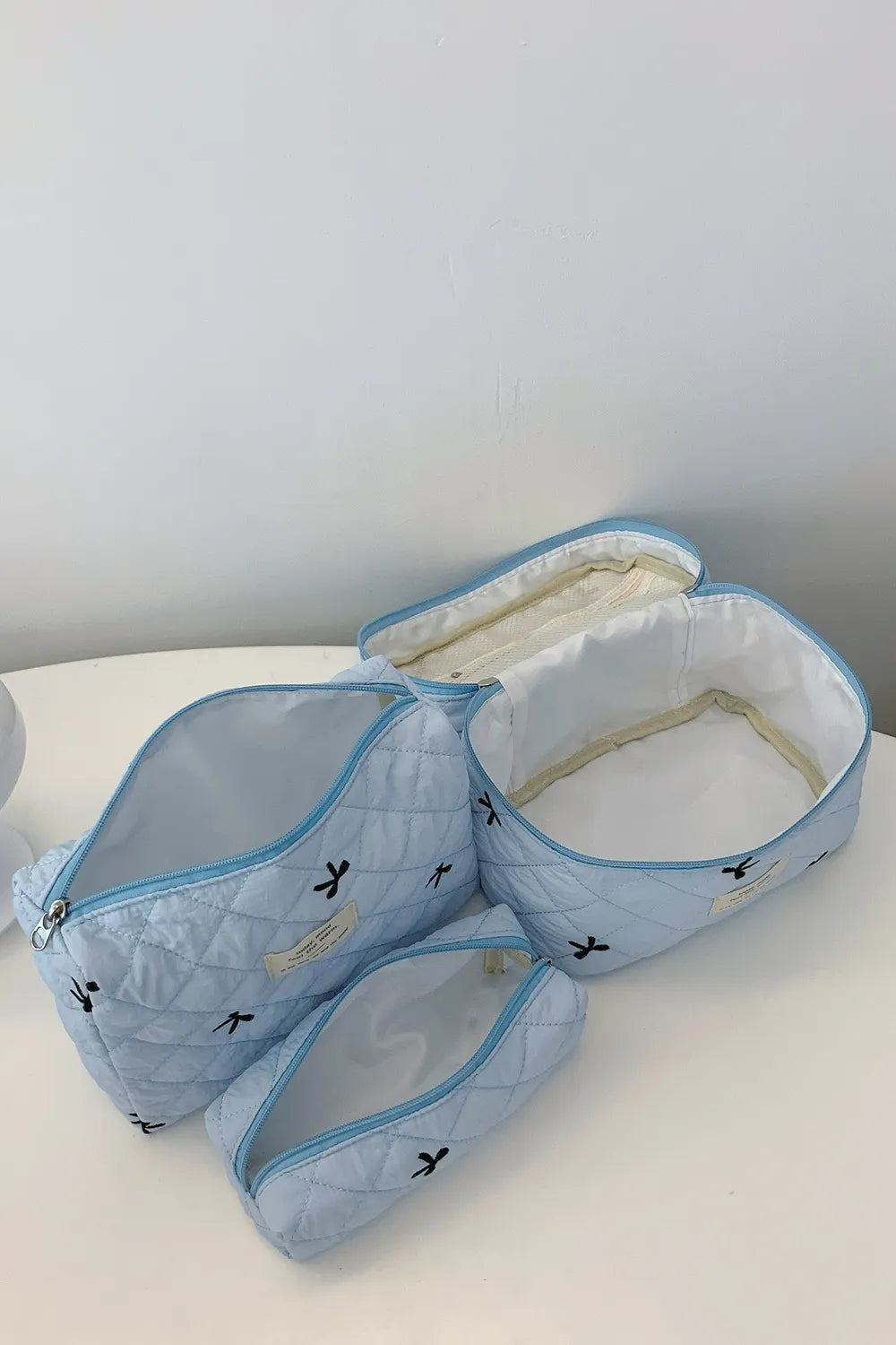 Light blue quilted storage set opened: large and medium zip bags plus small pouch