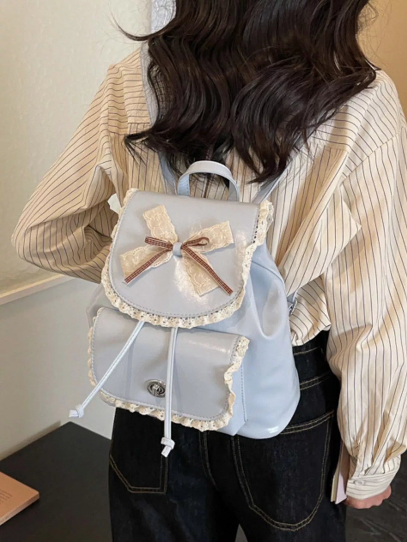 Light blue lace bowknot backpack worn with front flap, lace edge trim, drawstring cords