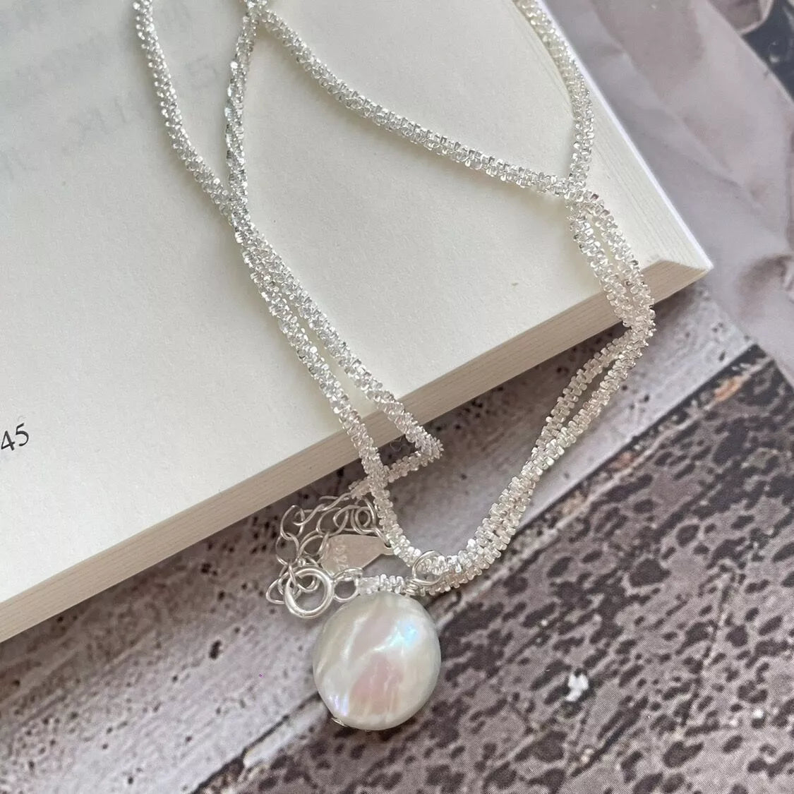 Layered silver chain necklace with bezel-set pearl centerpiece pendant