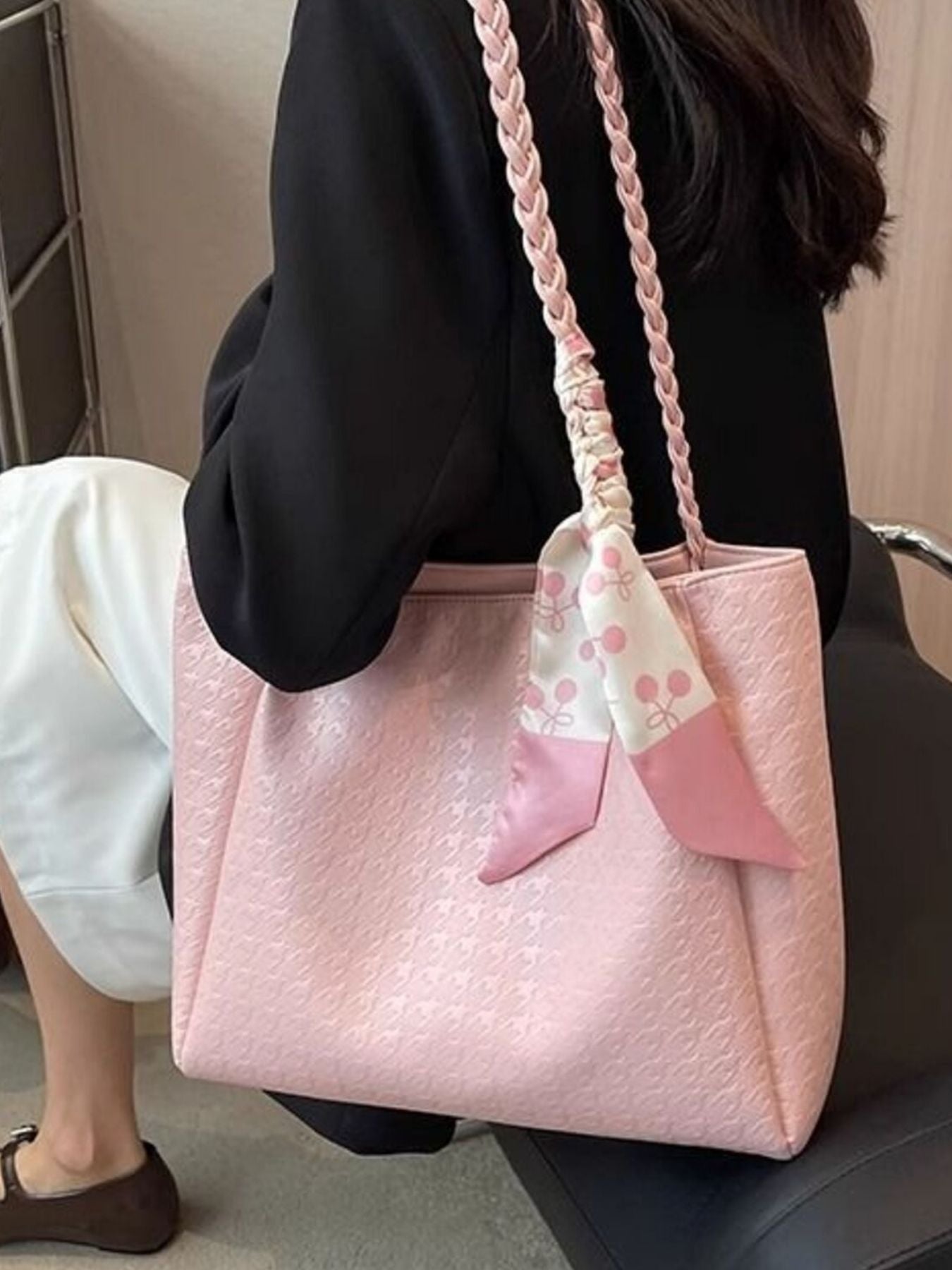 Blush pink braided handle tote bag held by model, ribbon bow at front