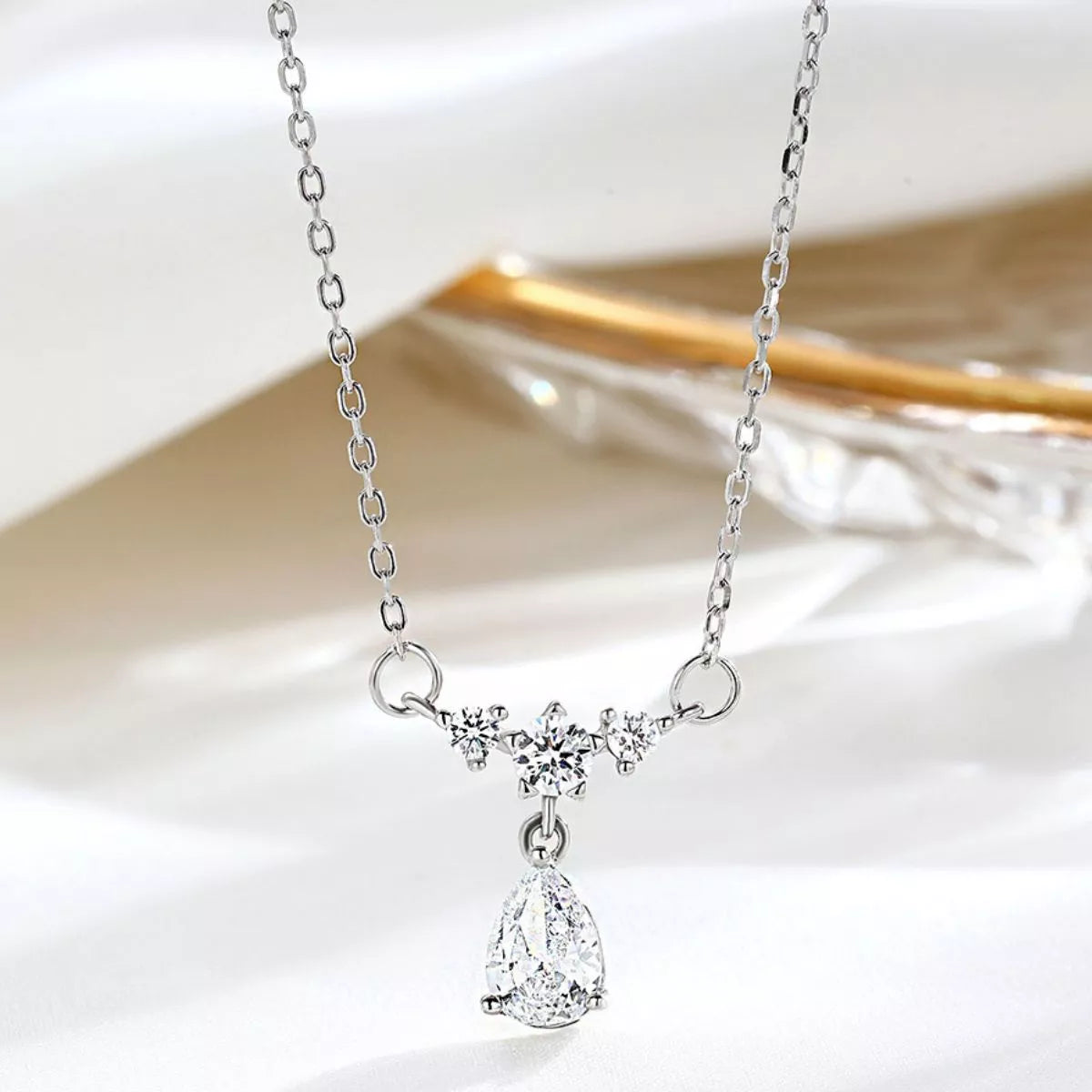 Silver teardrop zircon pendant necklace with small clustered stones along the chain