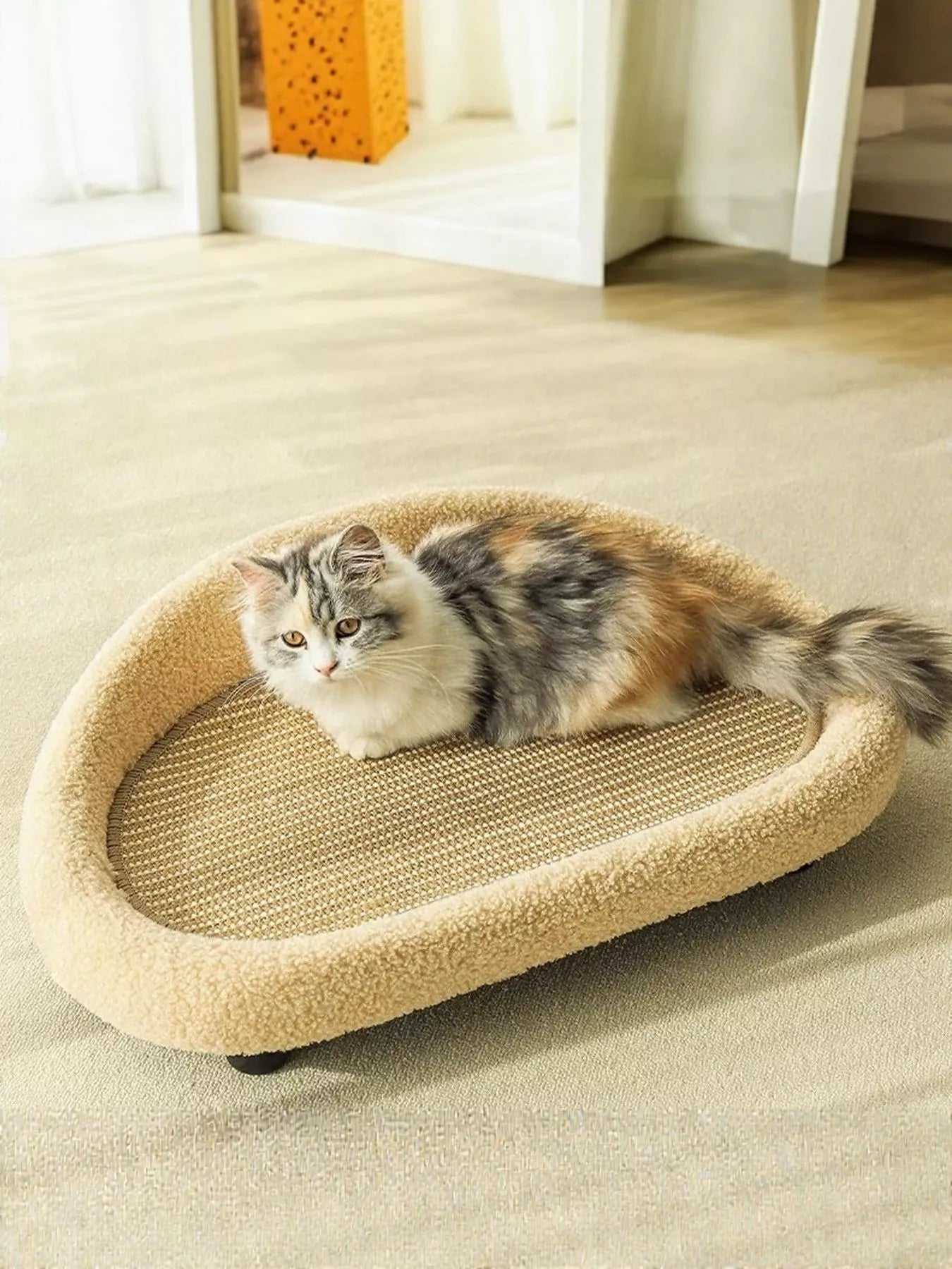 Tan cat scratching bed with oval sisal pad, cat lying inside