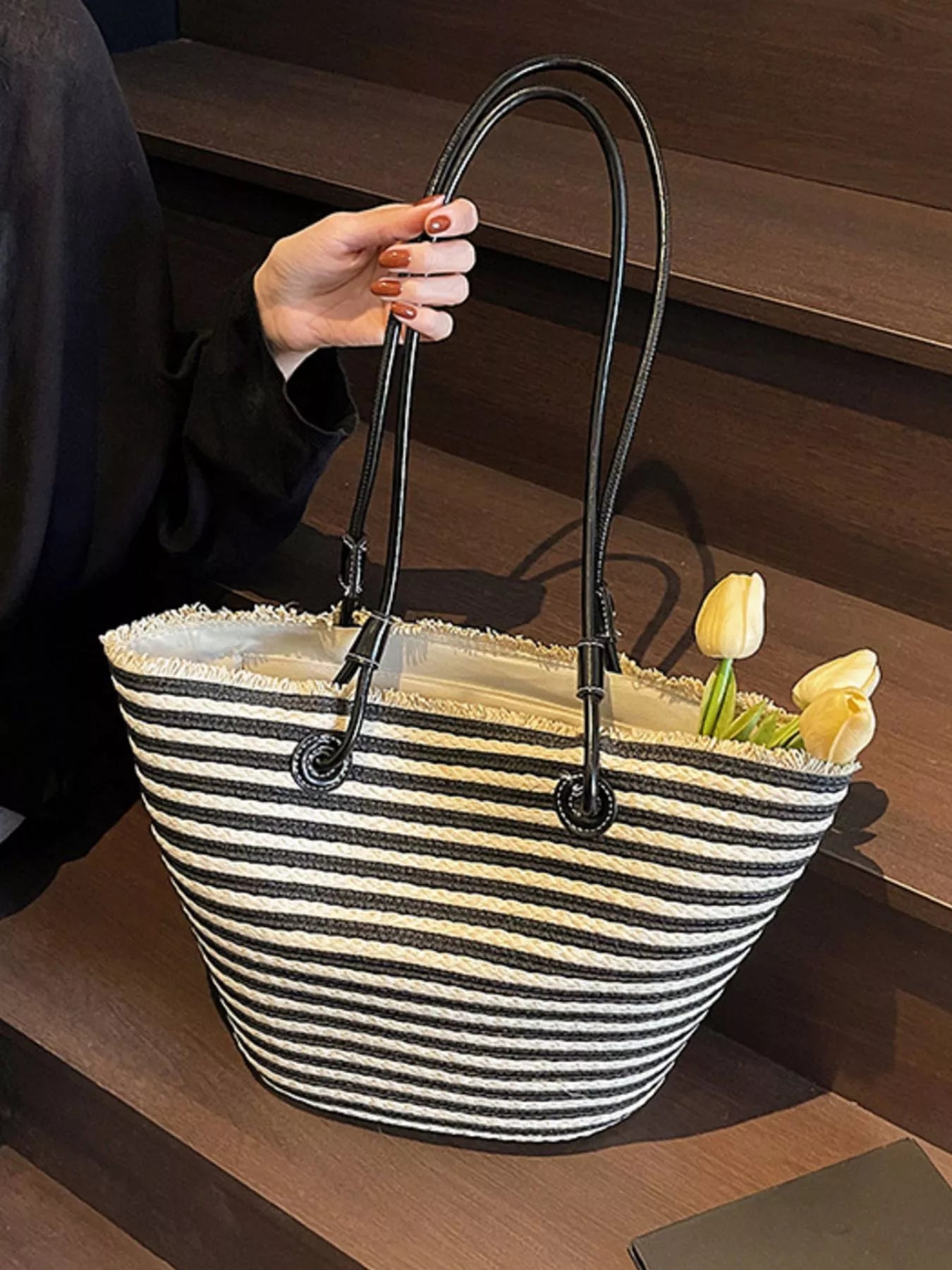 Striped woven straw tote with black grommet handles and open top