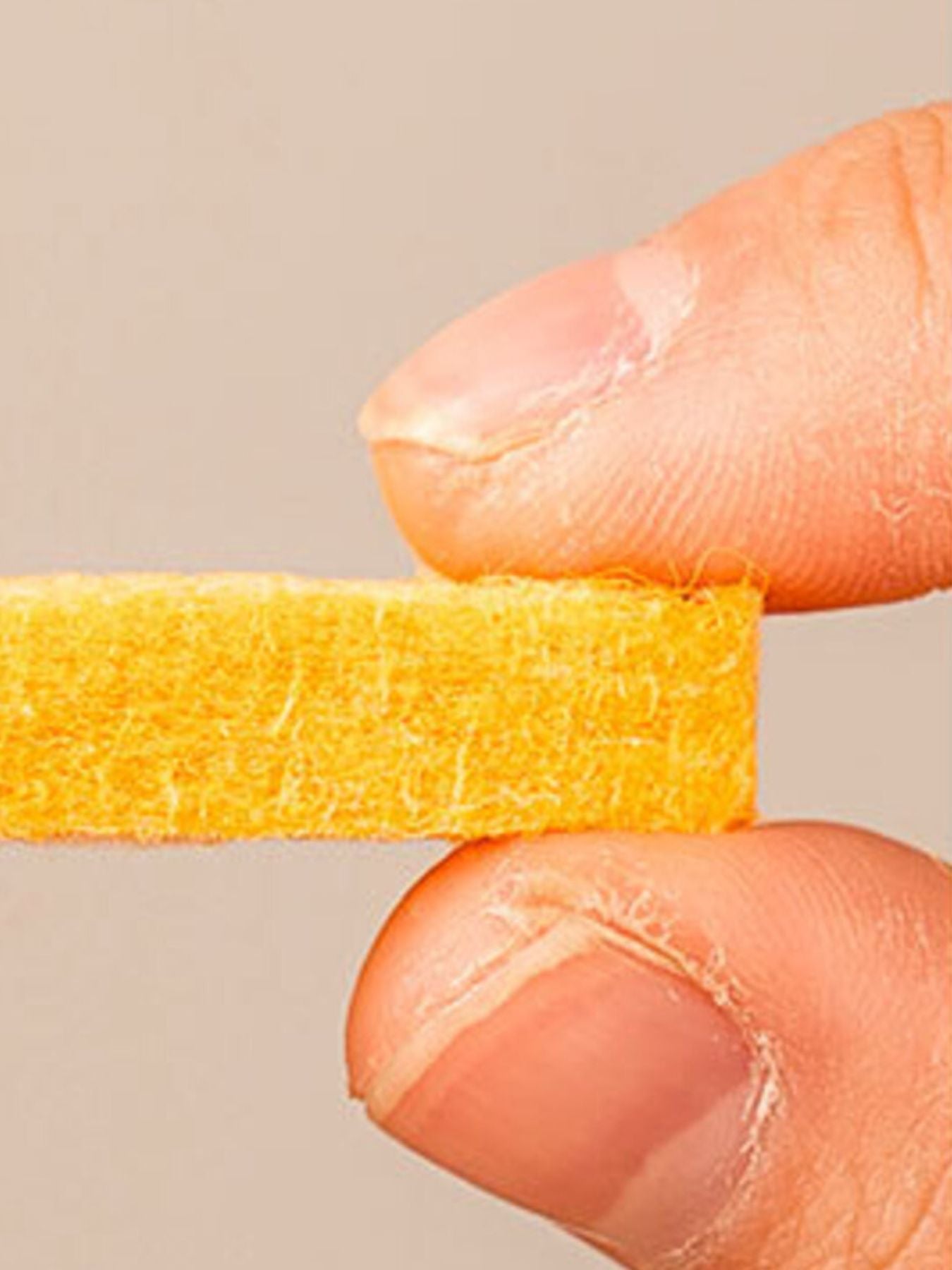 Close-up of orange fuzzy felt cat house surface and hand pressing down