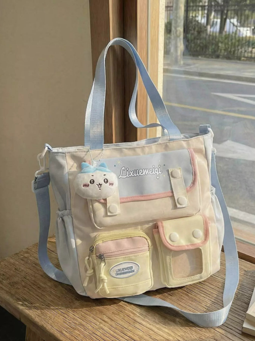 Multi-pocket shoulder bag in light neutral tones with pastel blue strap and front pockets