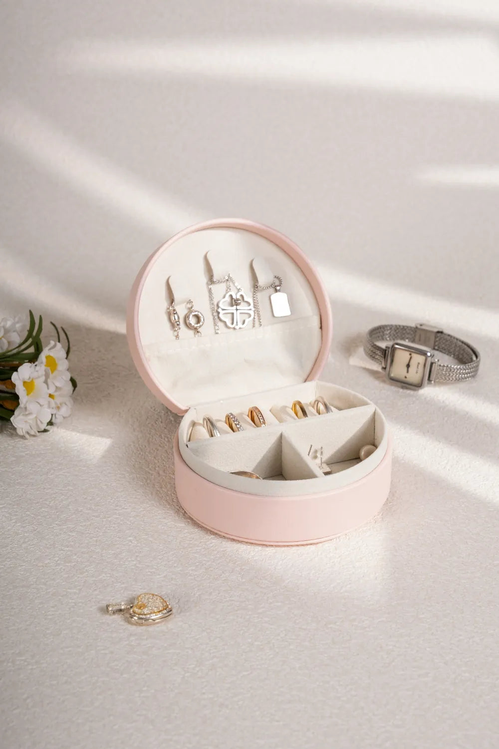 Blush pink PU leather travel jewelry box open, jewelry arranged in molded sections
