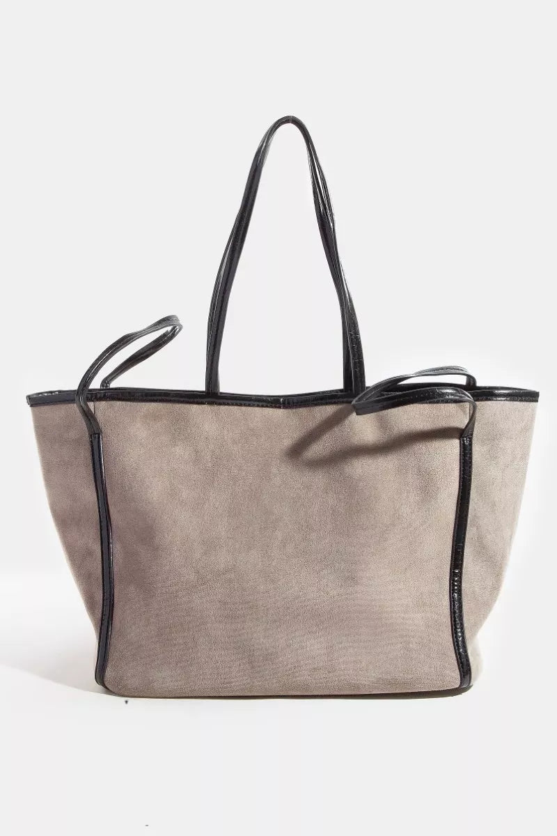 Taupe suede tote bag with black faux-leather trim and dual top handles, angled view.