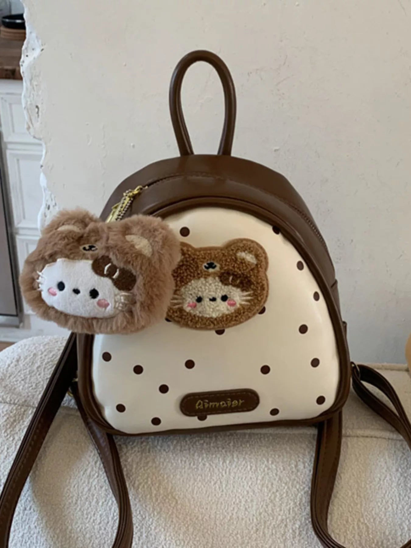Brown mini backpack with bear face appliqué, plush keychain, and double shoulder straps