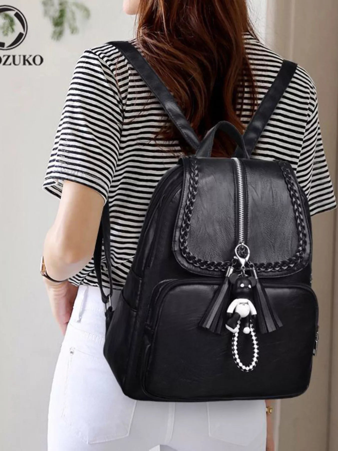 Black leather backpack bag with front flap, zipper closure and braided chain trim