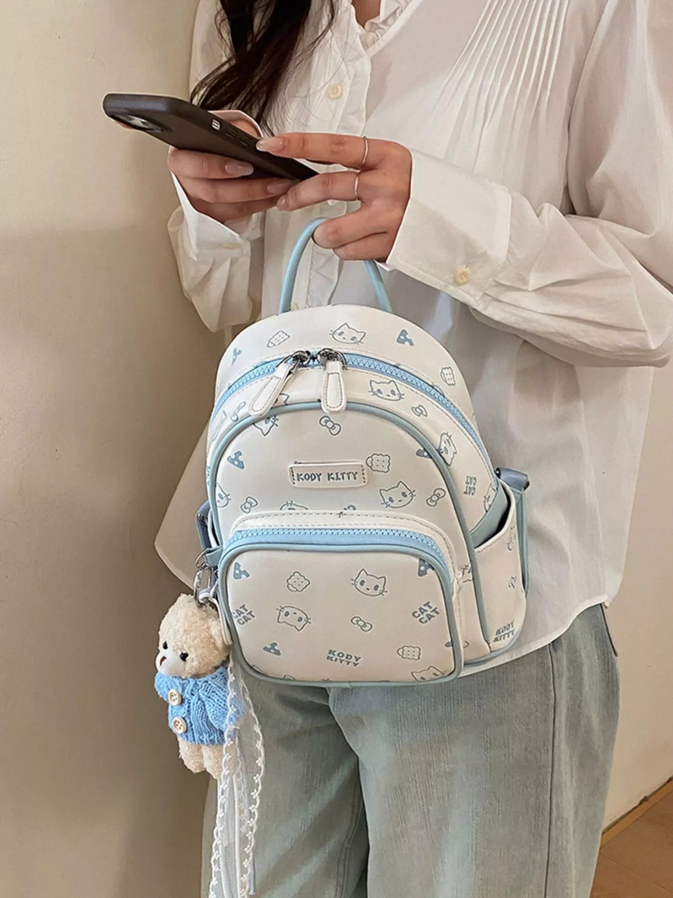 Pastel blue cartoon cat backpack with top handle, front zip pocket, and keychain charm