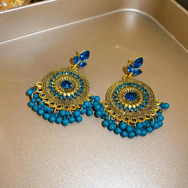 Cerulean beaded dangle earrings with filigree round center and blue rhinestone accents