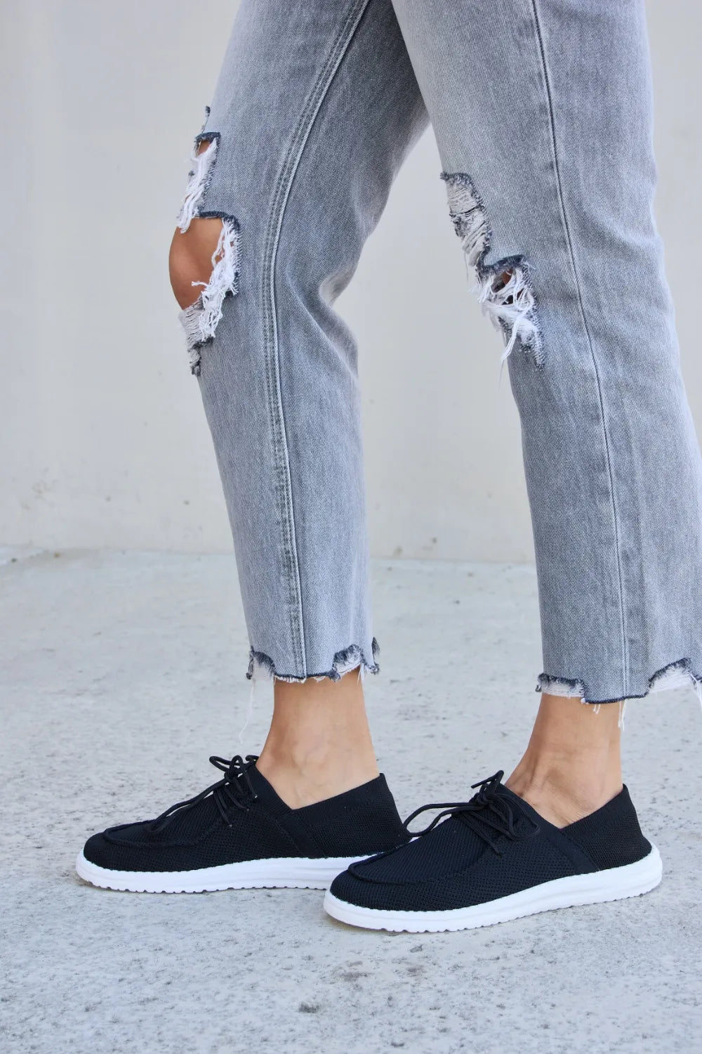 Black lace-up sneakers with textured uppers and white rubber sole
