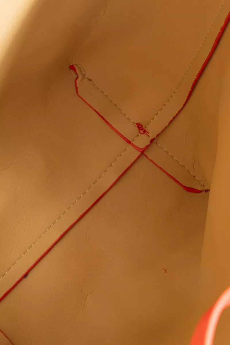 Faux suede tote close-up: red stitched panel with cross-stitched cord