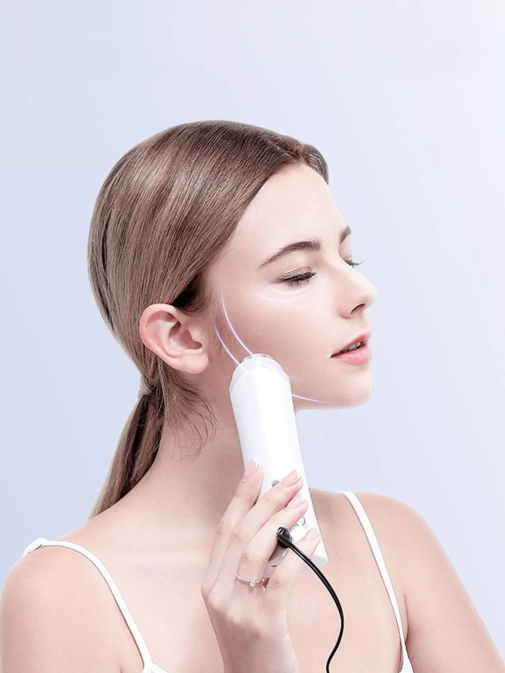 White facial skin tightening device used on cheek with oval massage head