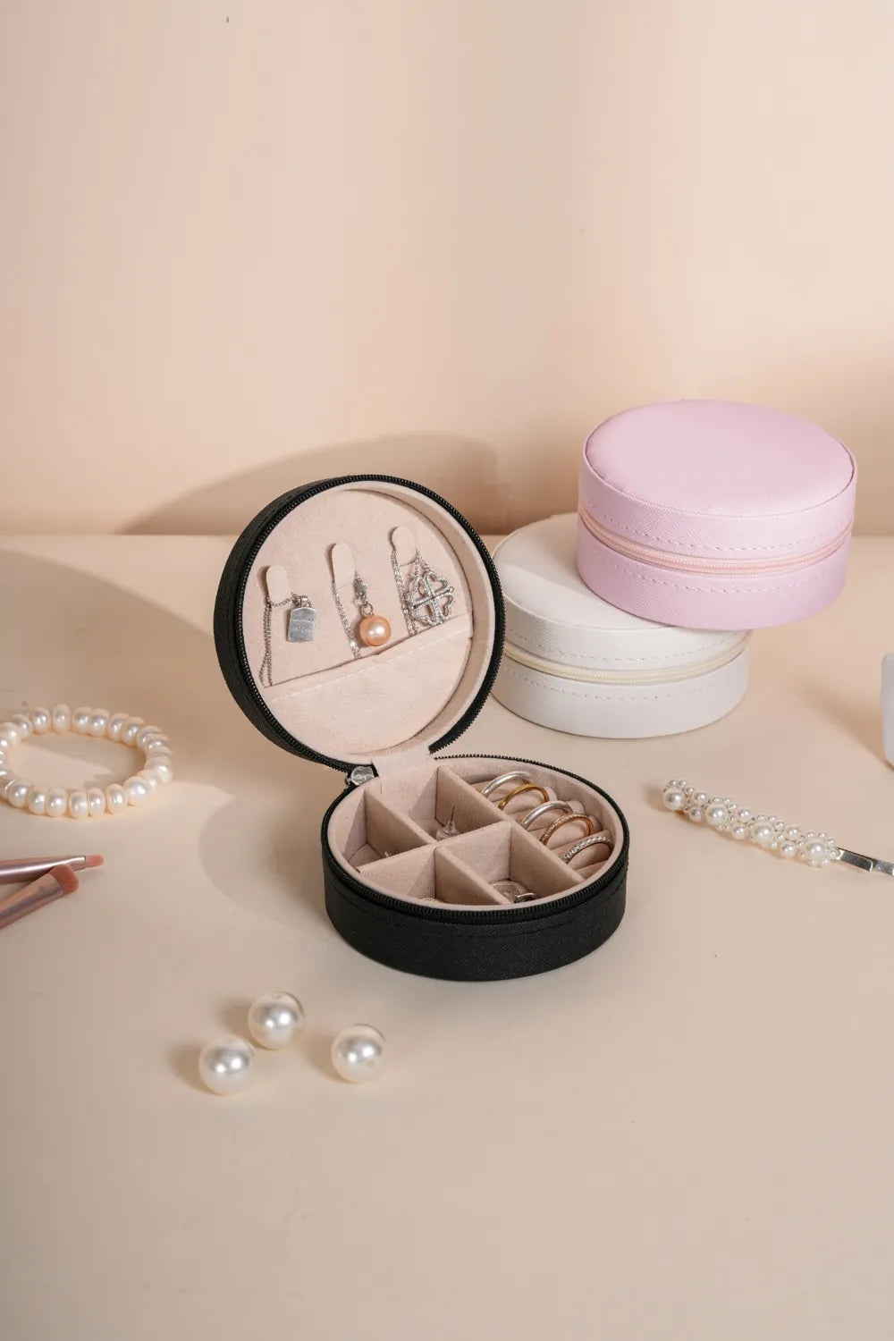 Black PU leather jewelry box with open round lid and blush pink inner compartments