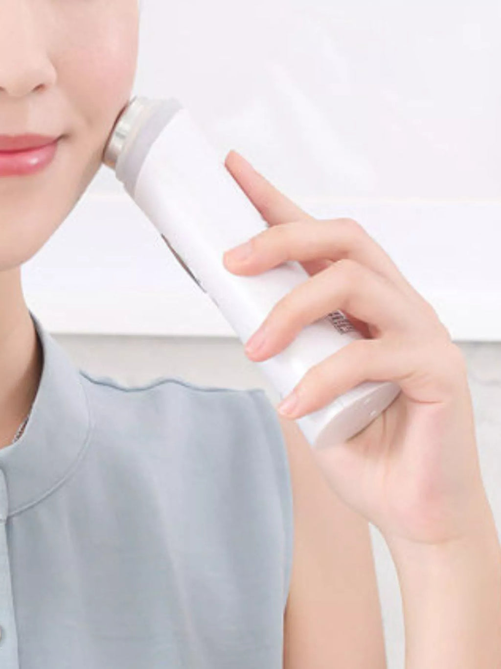 Hand holding white facial tightening device while gliding over neck skin