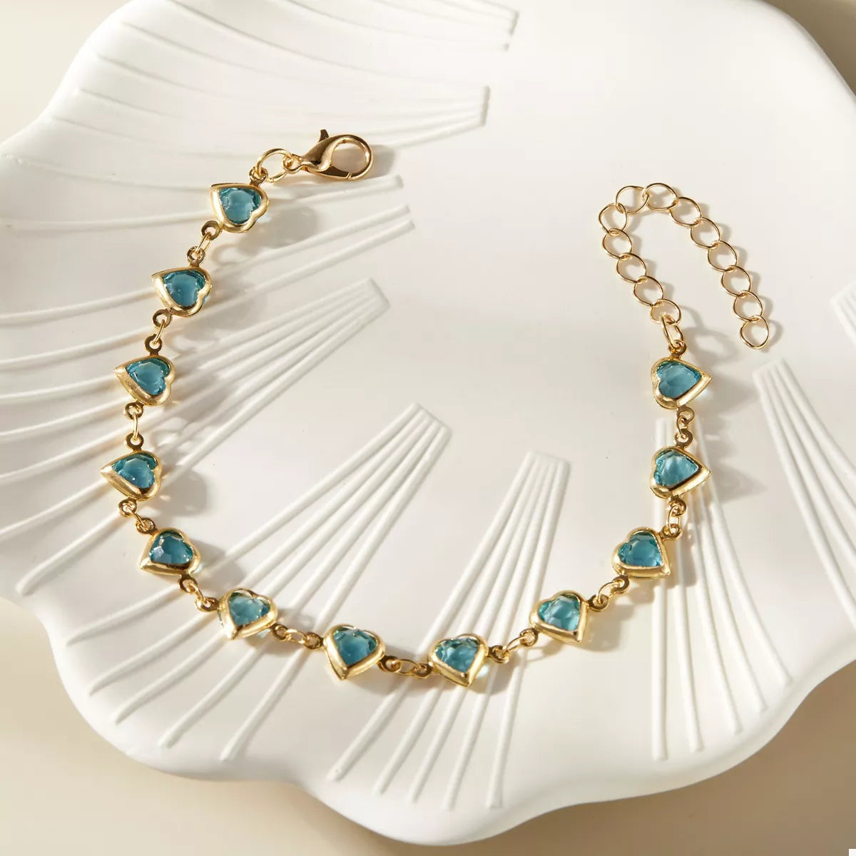 Gold heart bracelet with teal heart charms, linked chain and secure clasp