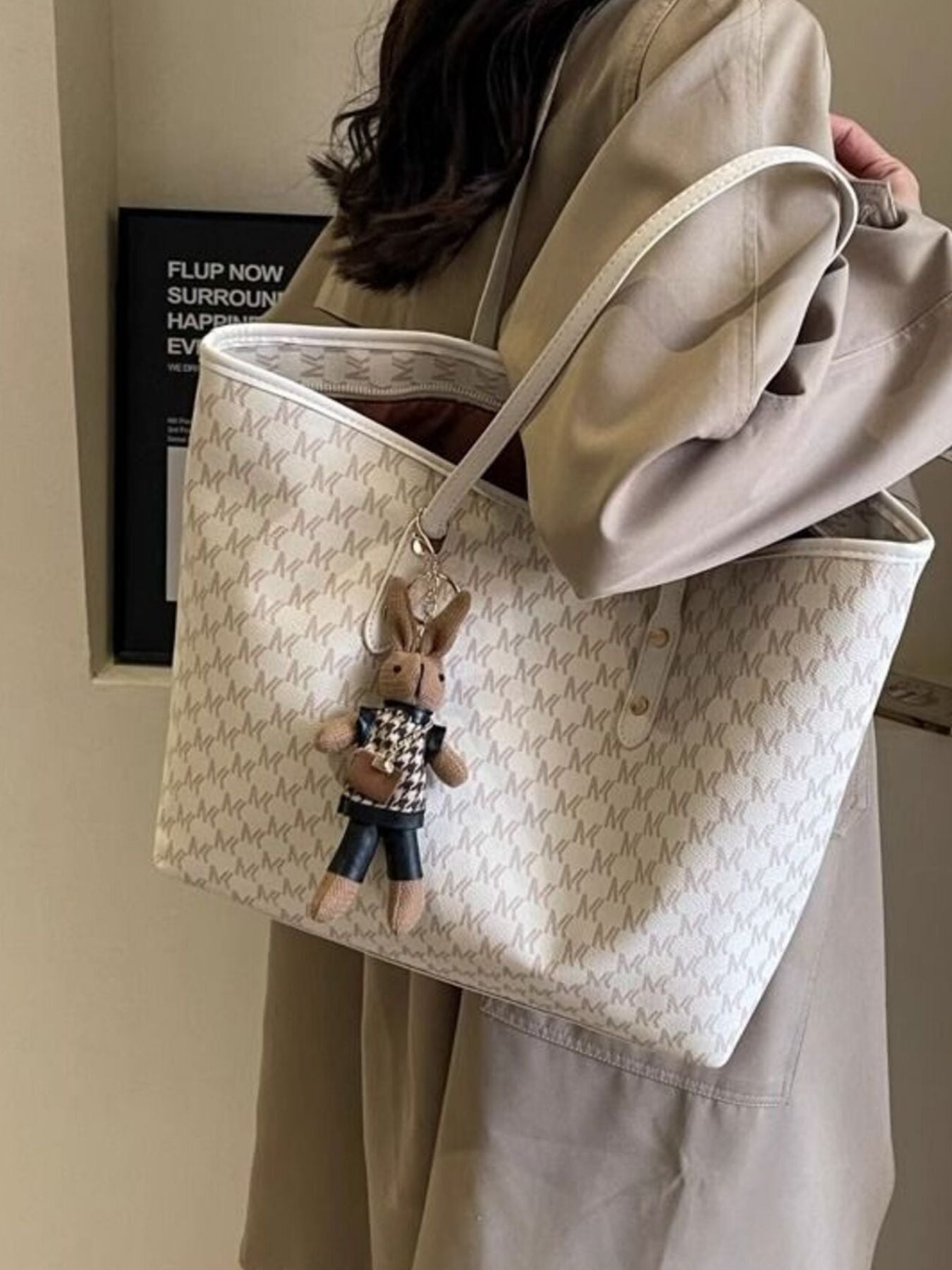 Beige monogram tote bag with top handles, open interior, small hanging rabbit charm