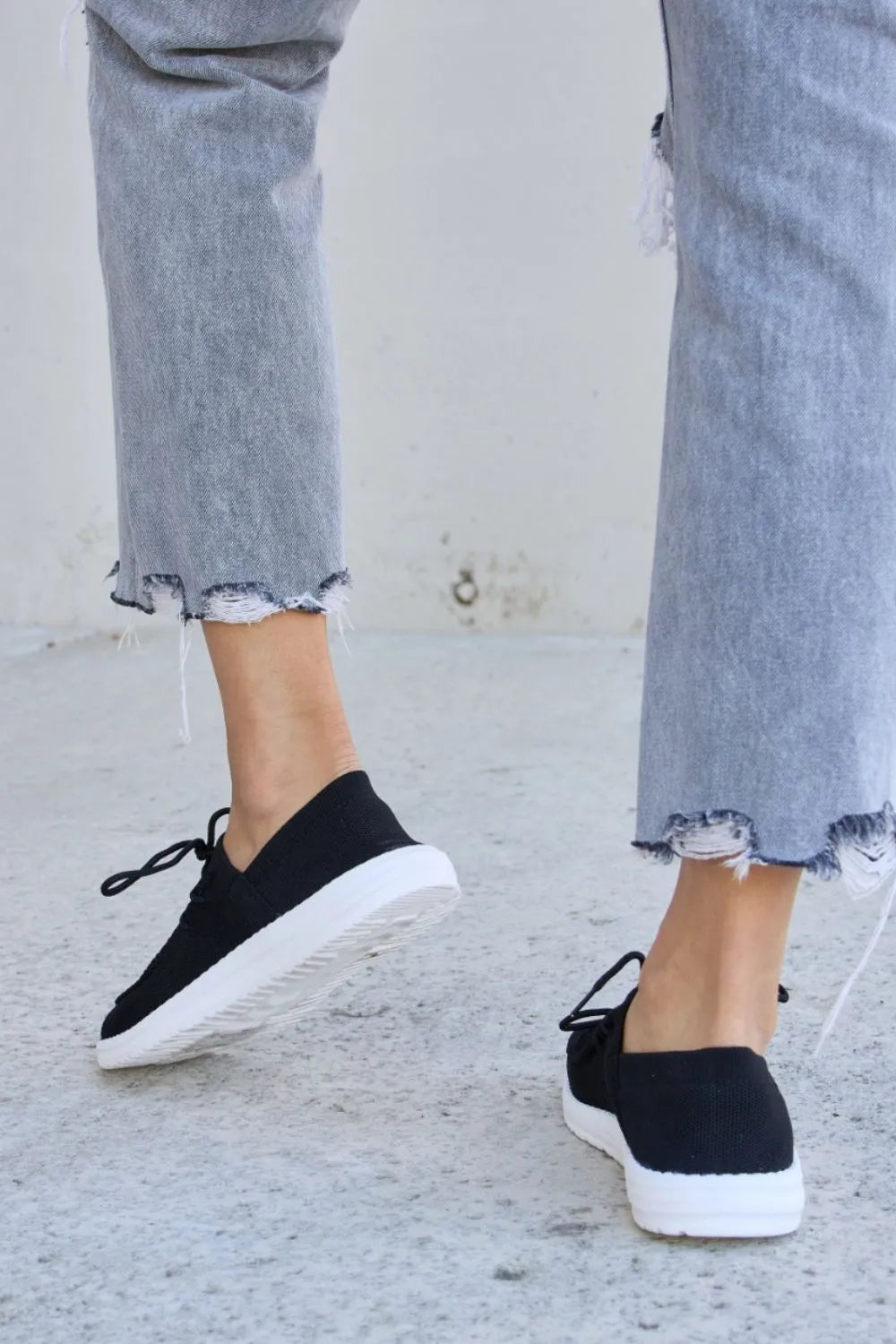 Black low-top sneakers, lace-up front with round toe and white sole