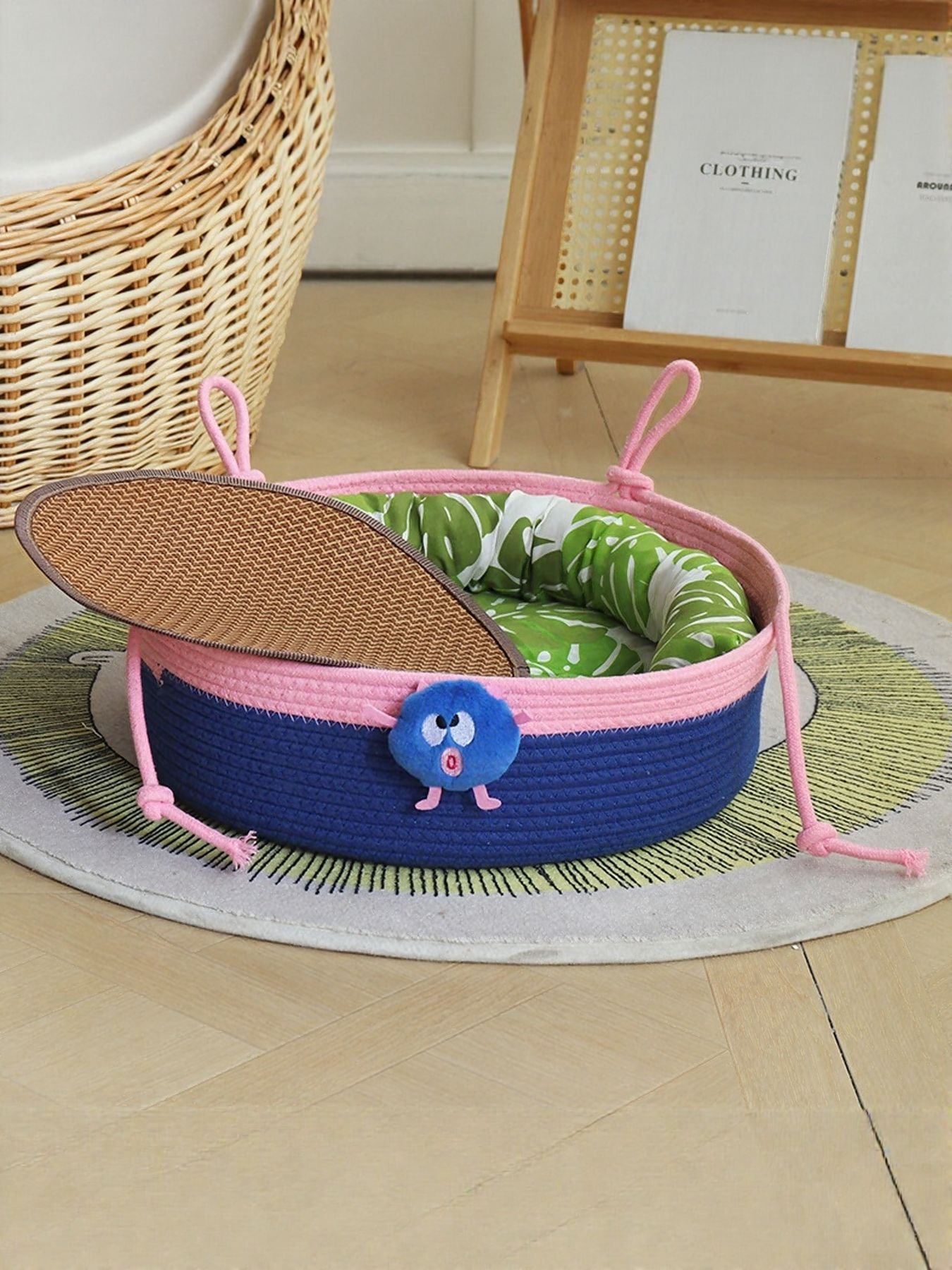 Two-tone woven pet nest with blue and pink trim, green patterned inner cushion visible