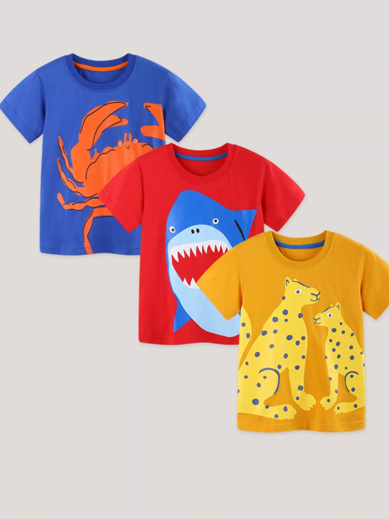 Drei Kinder-T-Shirts im Set: blaues Delfin-/Meerestiermotiv, rotes Hai-Motiv, gelbes Tiermotiv