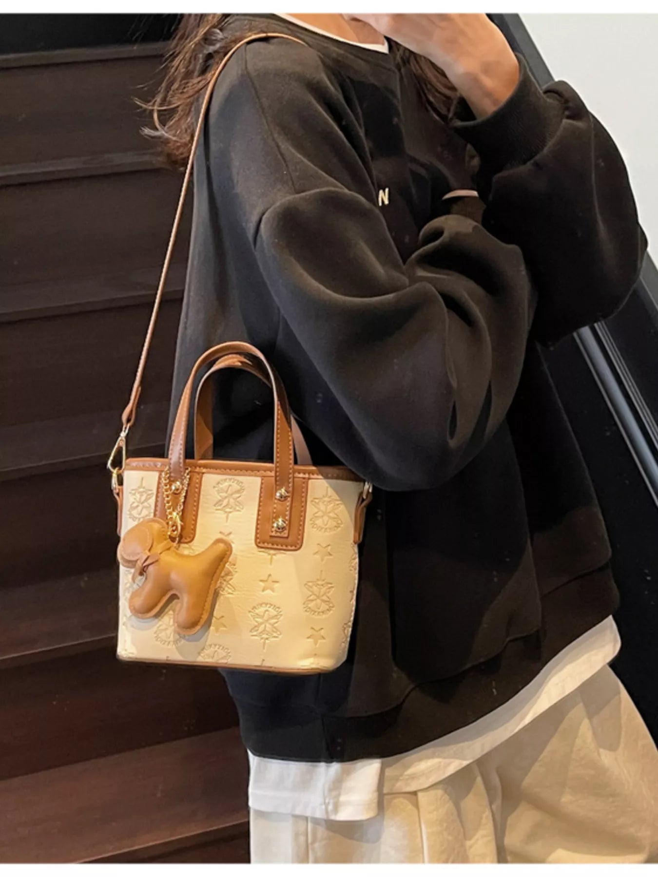Beige Handtasche mit Reliefprägung, Hund-Anhänger und goldenen Nieten an den Riemen