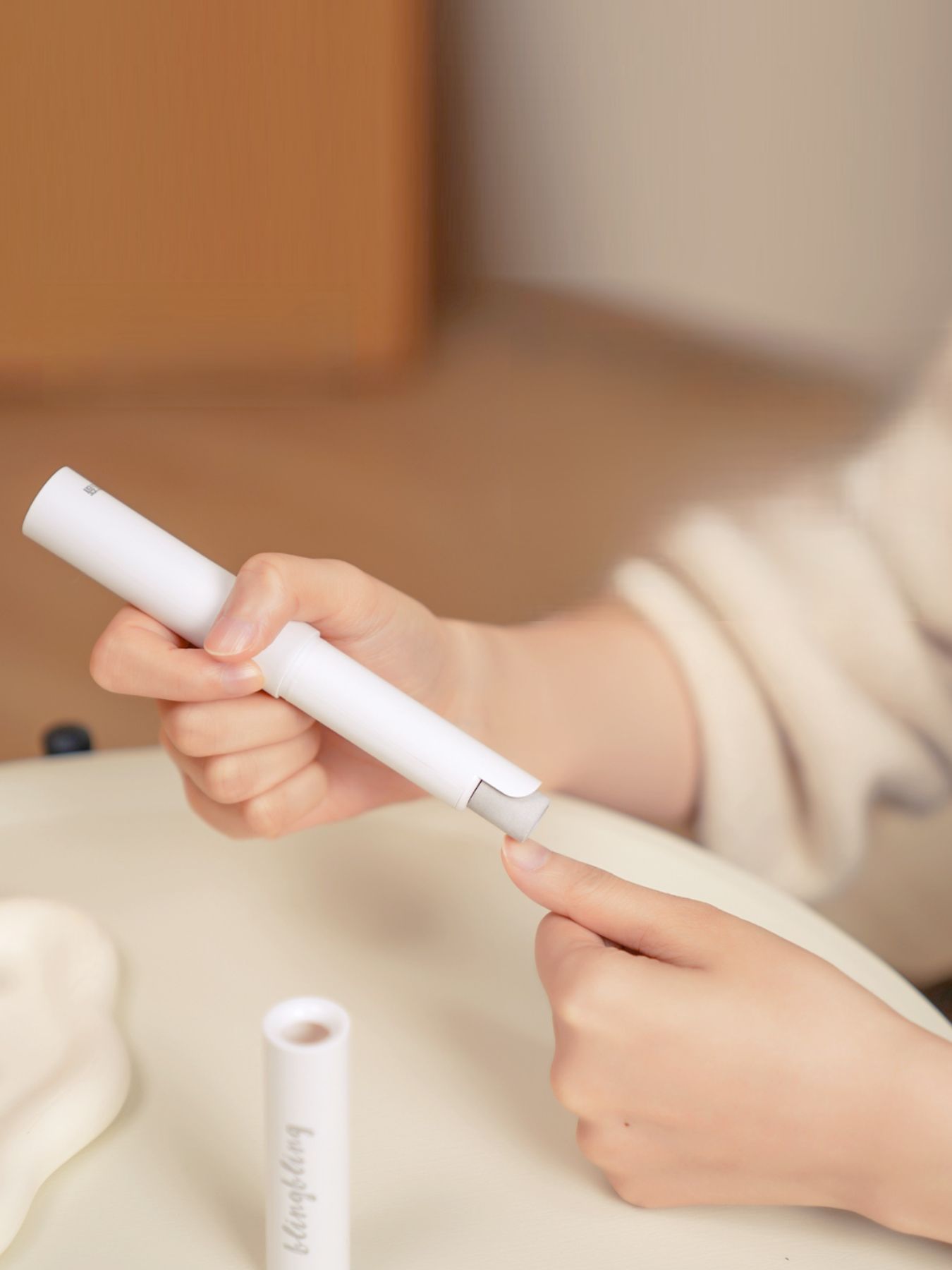 White electric nail buffer in use, held above nails