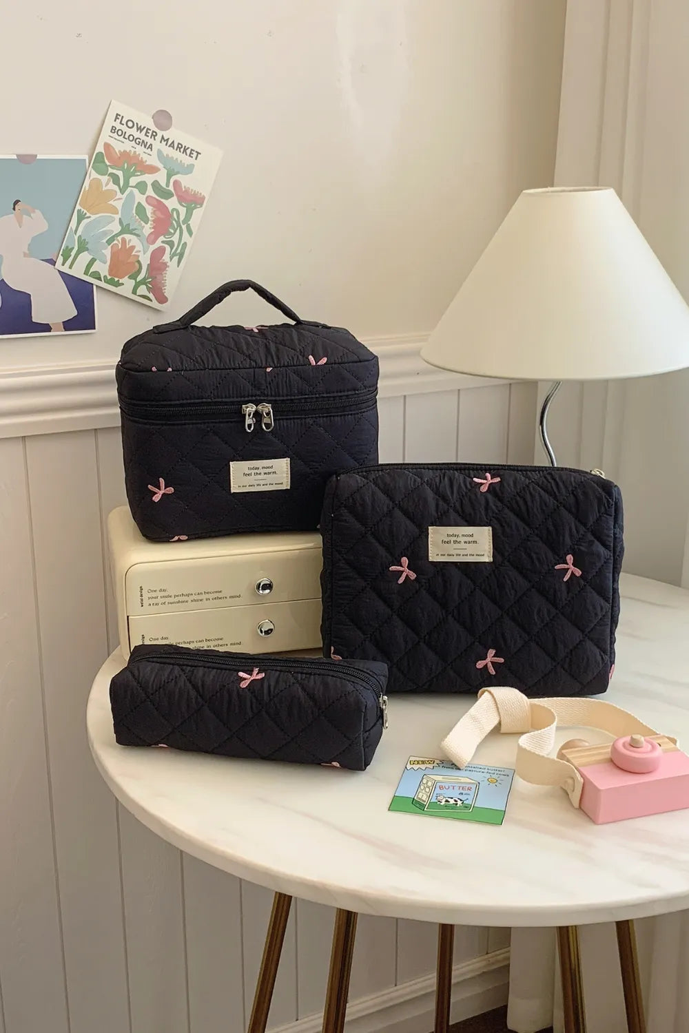 Black quilted 3-piece storage bag set with bow pattern and zip closures.