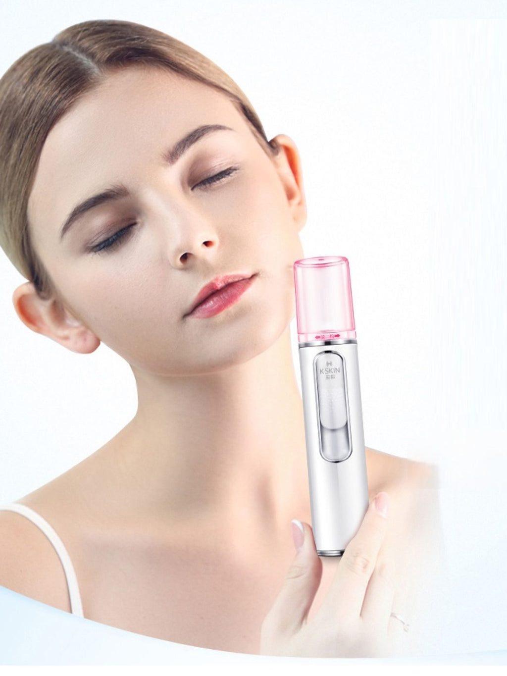 Facial mister sprayer held to cheek with pink nozzle cap on white body