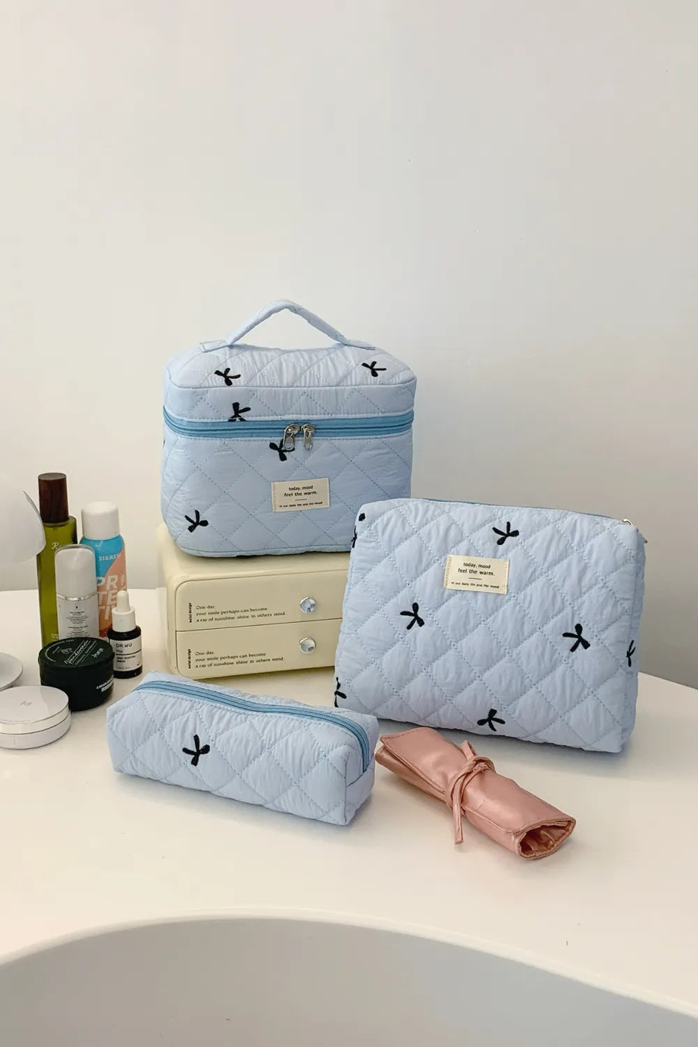 Light blue quilted storage bag set with bow pattern, zip tops, 3-piece.