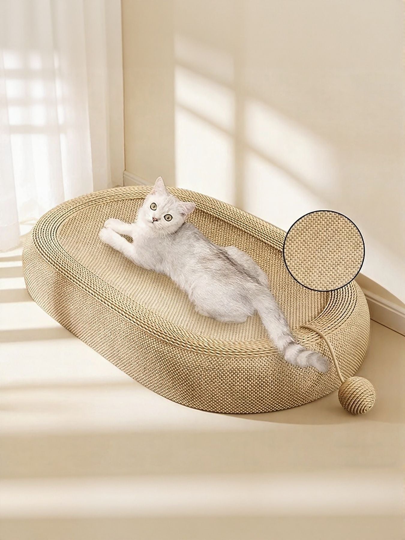 Beige oval cat scratching bed with white cat lying on the woven surface