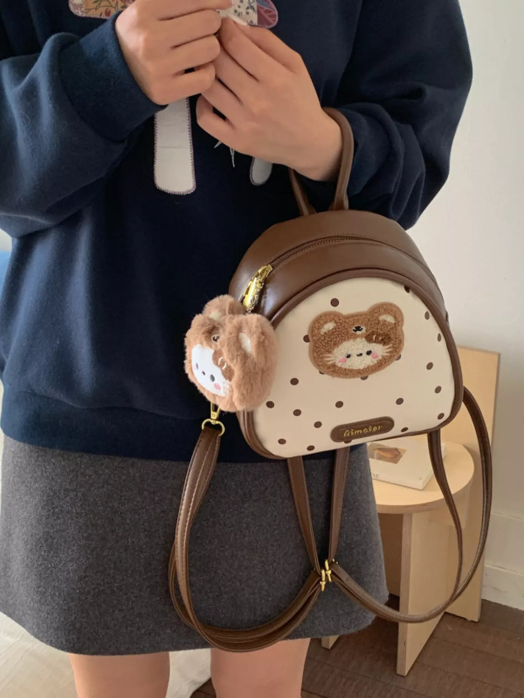 Brown mini backpack with bear appliqué on white dotted panel and front zip detail