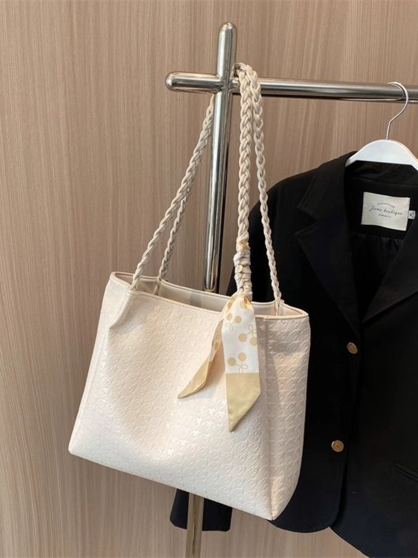 Ivory braided handle tote bag hanging on a rack with ribbon bow