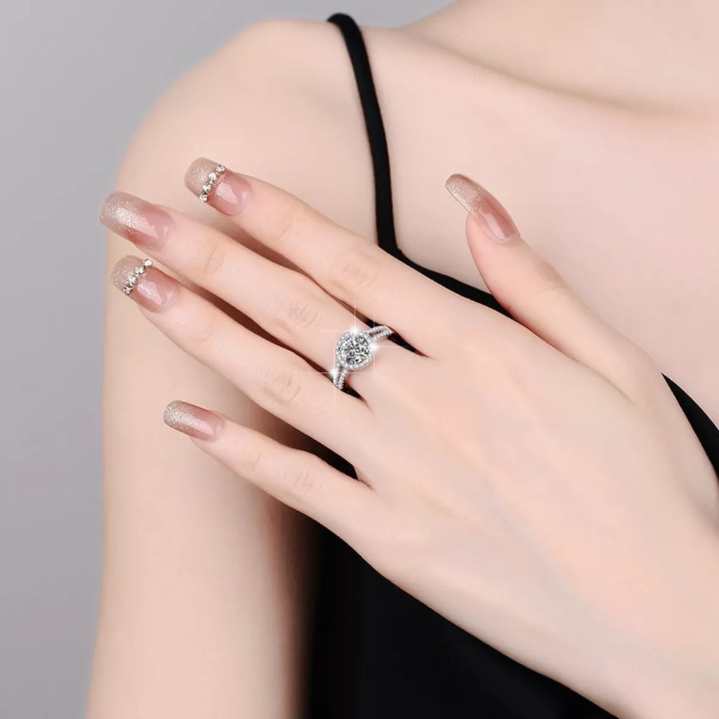Moissanite halo ring on hand with sparkling stone cluster and pavé side details
