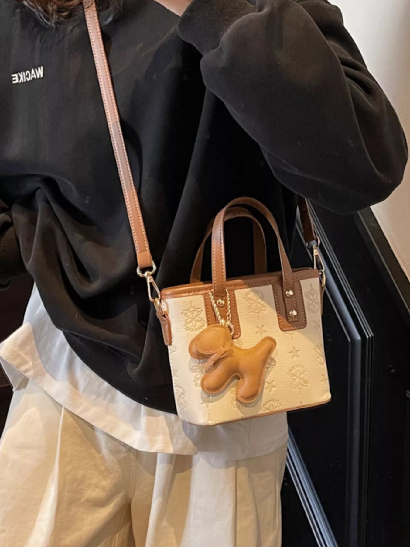 Beige Crossbody-Tasche mit langen Riemen, Reliefmuster und Hund-Anhänger vorne
