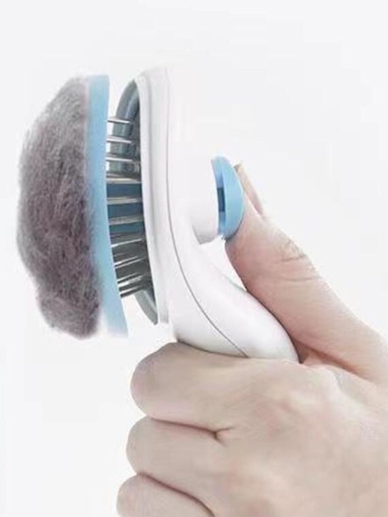 Hand using blue pet hair remover comb on fabric; round brush head with metal pins